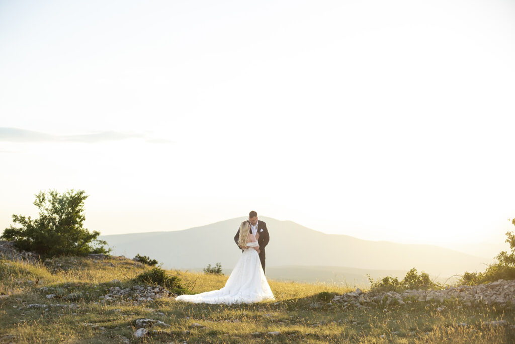 Wedding couple hugging on a top of mountain during sunset.